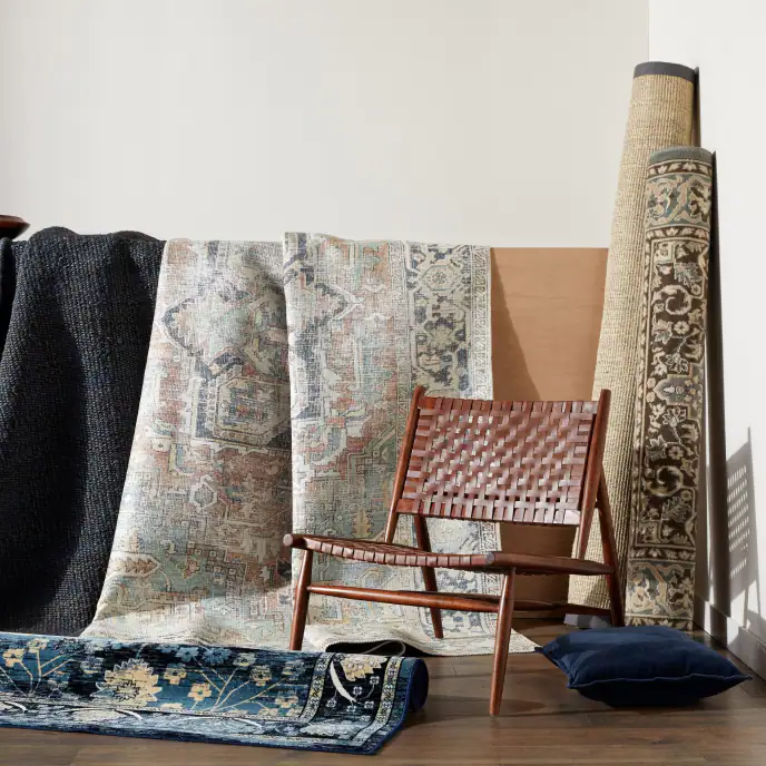 several rolled up and hung up rugs against a wall next to a chair for sale online at overstock