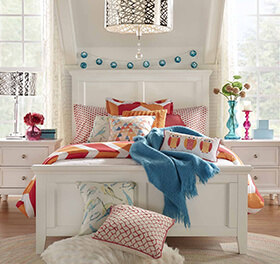 Decorated teen bedroom with bed, nightstand, and throw pillows
