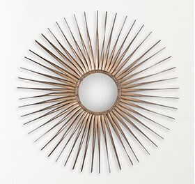 Bronze metallic starburst mirror hanging above a console table. 
