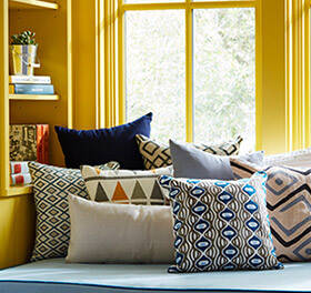 Yellow window seat with an assortment of throw pillows. 