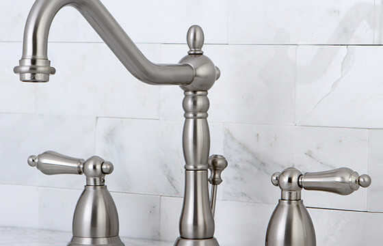 Satin nickel bathroom faucet with a white marble backsplash. 
