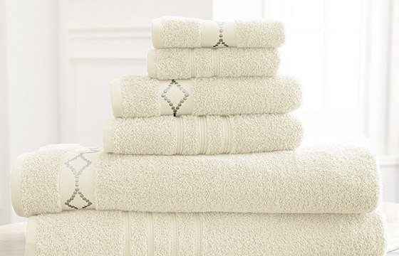 A set of ivory bath towels on a bathroom counter. 