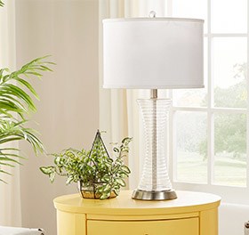 Yellow end table with a  clear table lamp on top.