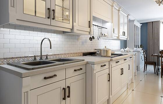 A kitchen with white cupboards and bronze hardware. 
