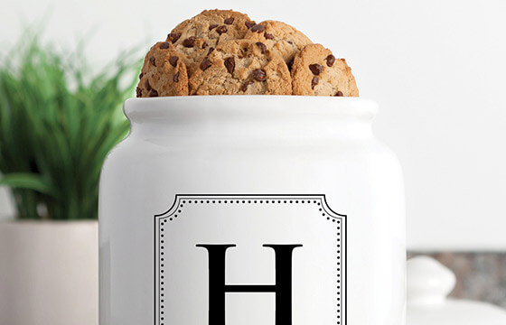 A white cookie jar with cookies in it, along with a monogrammed 