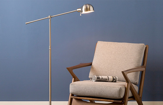 A mid-century modern living room chair with a silver floor lamp next to it. 
