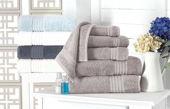 Stacked bath towels in gray, navy, white, and light blude