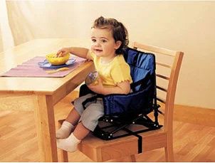 Cute baby girl sitting in a booster seat