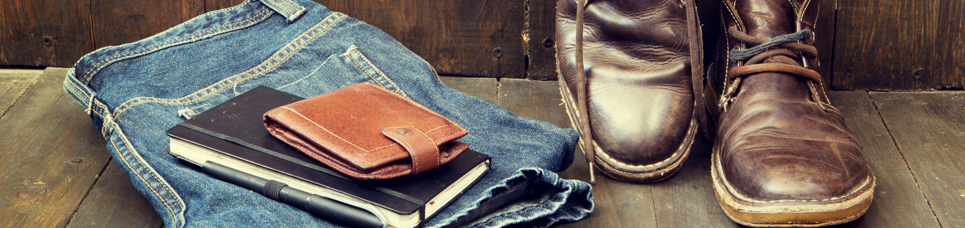 Brown leather boots next to jeans and a wallet