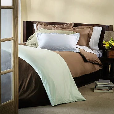 Unmade bed with brown, white, and mint bedding