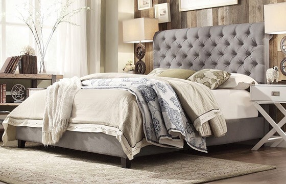 Grey upholstered bed with layers of bedding