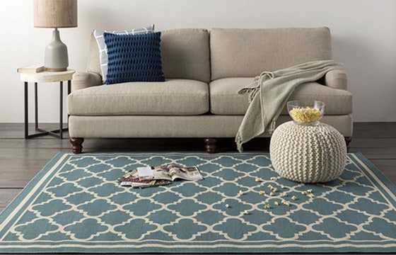 Sofa with blue trellis rug and cream pouf