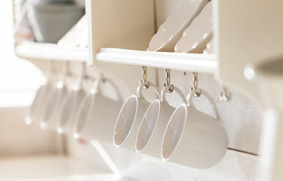 White shelf with coffee mugs hanging off hooks below