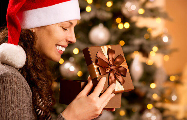 Woman opening gift with stocking stuffer ideas including a diamond ring, perfume, and wallet