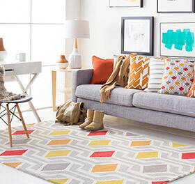 A living room with a bold colored geometric area rug on the floor. 