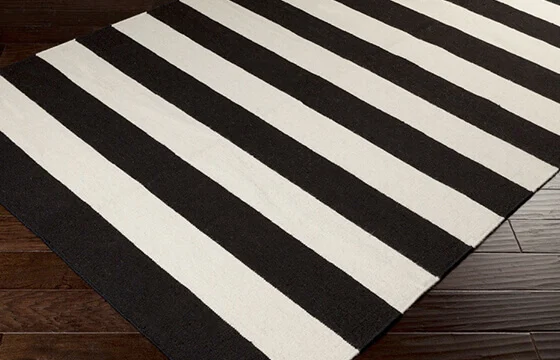 A black and white stripe area rug on dark wood floors 
