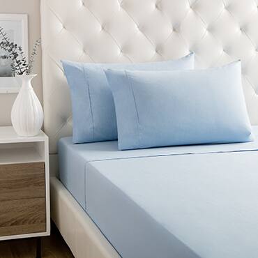 Blue percale sheets fitted on white tufted bed next to bedside table